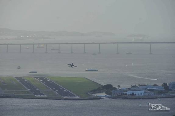 Avião decola do aeroporto santos Dummont, no Rio de Janeiro. Ao fundo, a ponte Rio-Niteroi